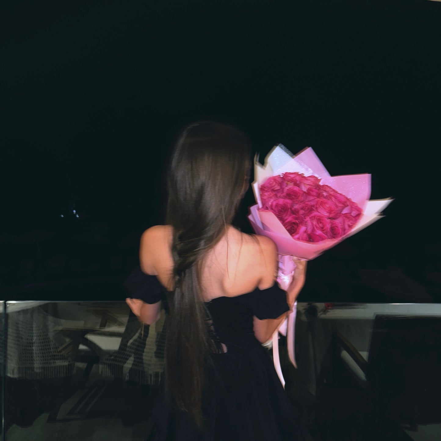 Woman holding a bouquet of pink flowers in front of a black car