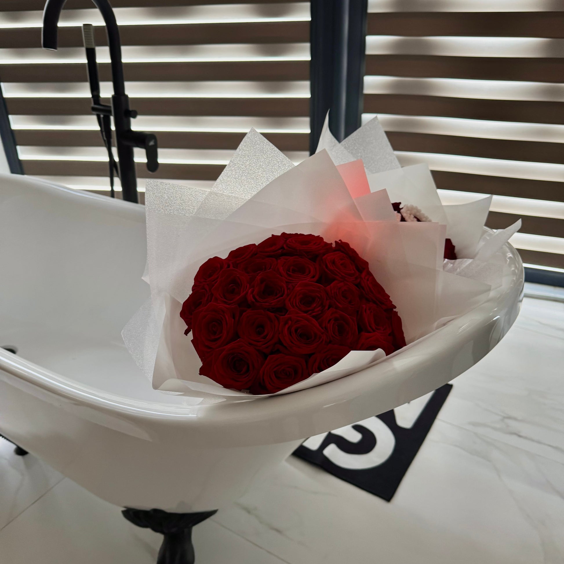 Bouquet of red roses in a white box on a white surface with a blurred background