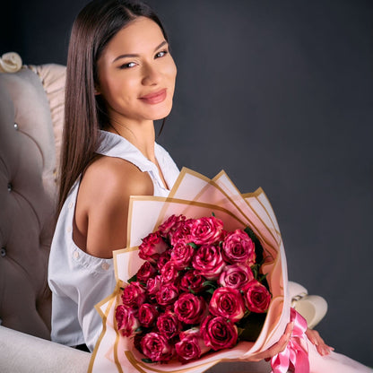 Woman holding a bouquet of red roses against a dark background