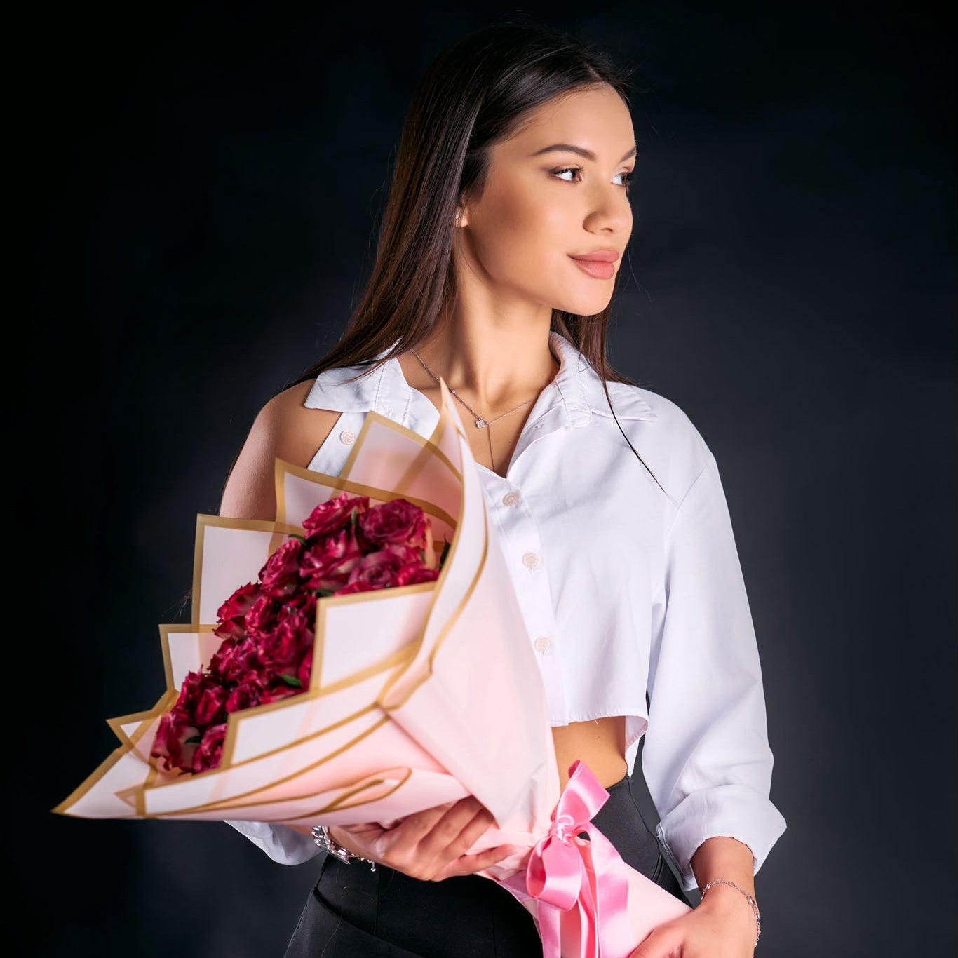 Woman holding a bouquet of red flowers against a black background
