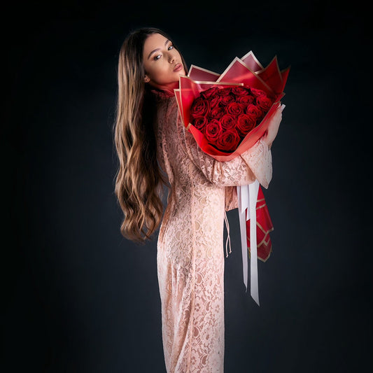 Woman holding a bouquet of red roses against a black background