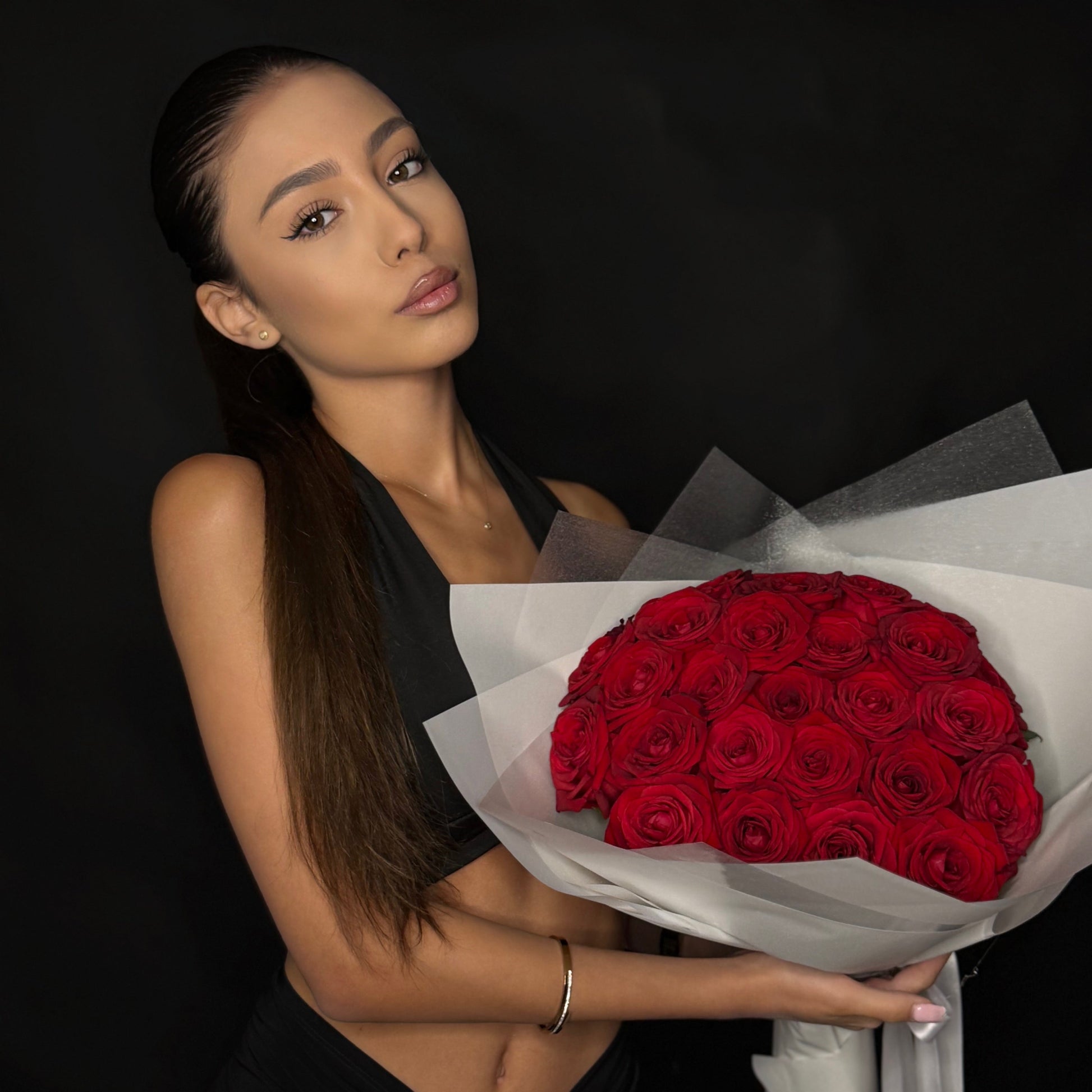 Woman holding a bouquet of red roses against a dark background