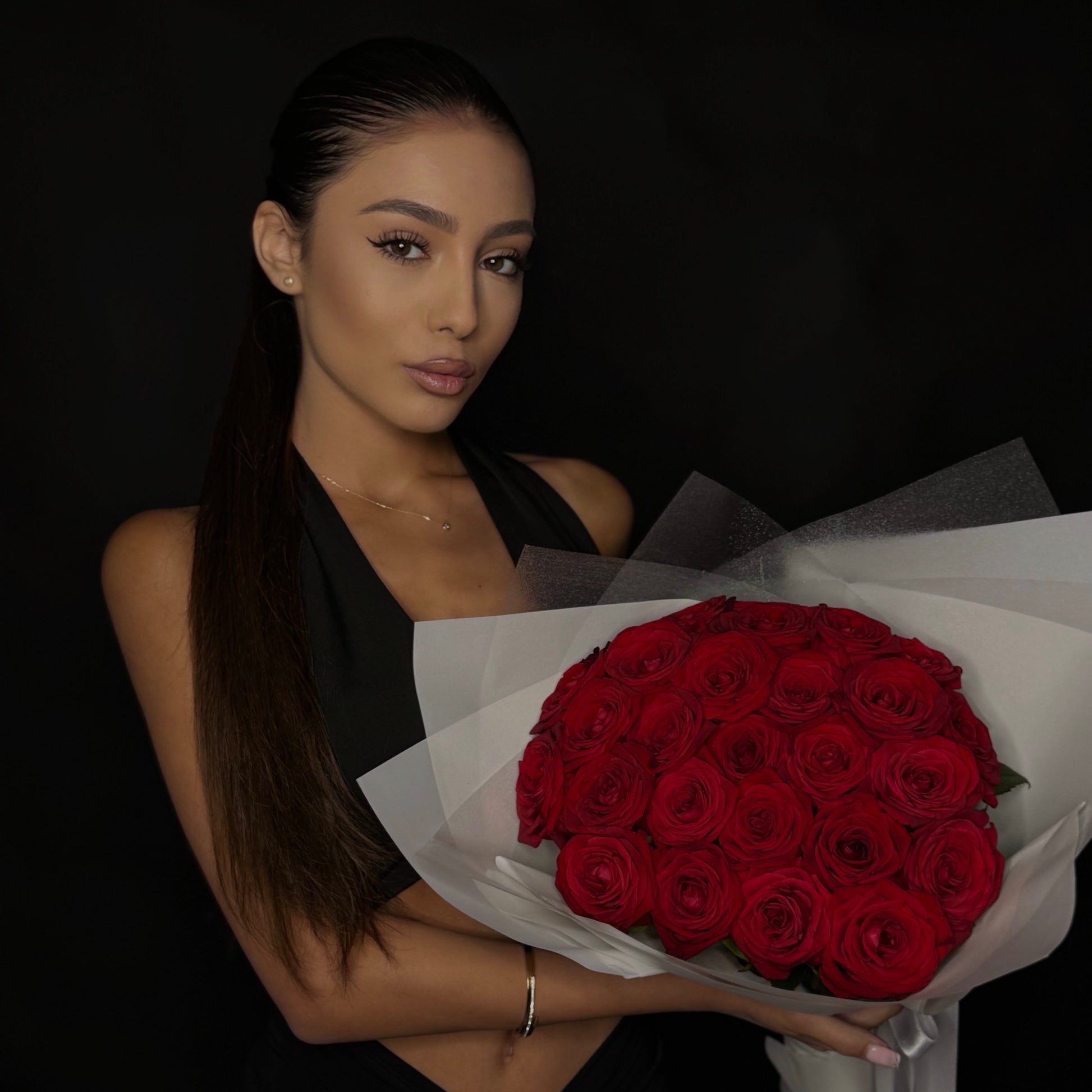 Woman holding a bouquet of red roses against a dark background