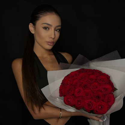 Woman holding a bouquet of red roses against a dark background