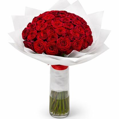 Bouquet of red roses in a clear vase with white paper wrapping on a white background