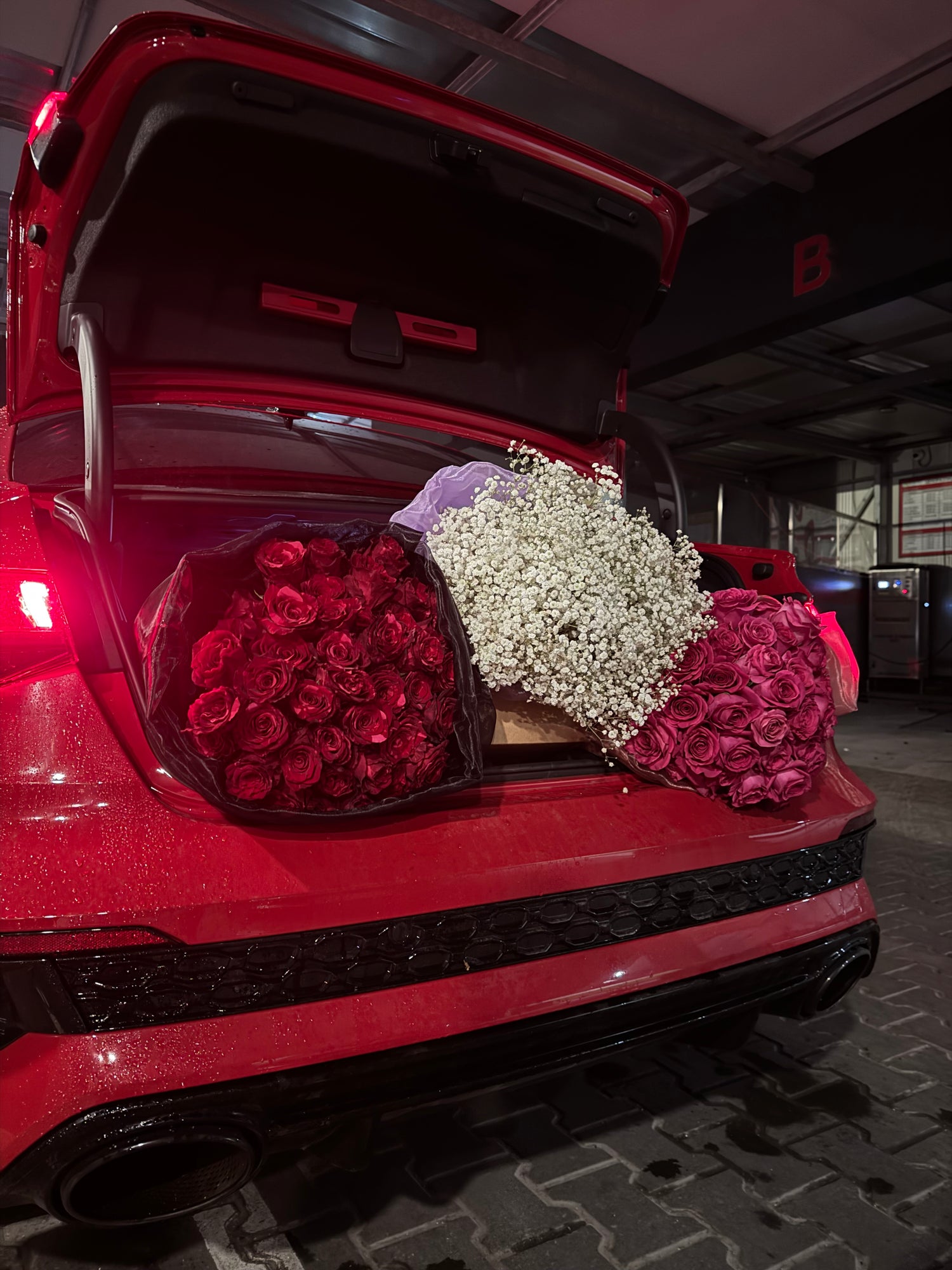 Red car trunk with three bouquets of roses inside