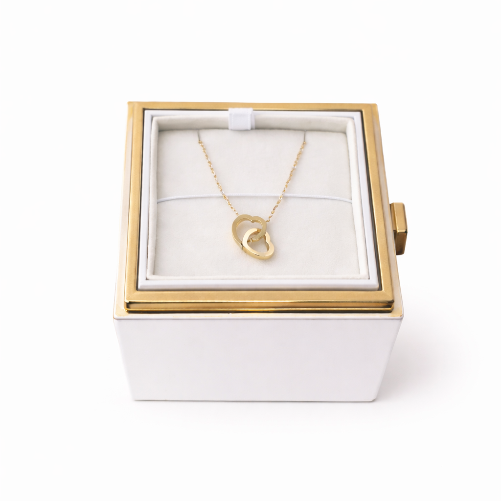 Gold necklace with a heart pendant in a white jewelry box with gold trim on a white background