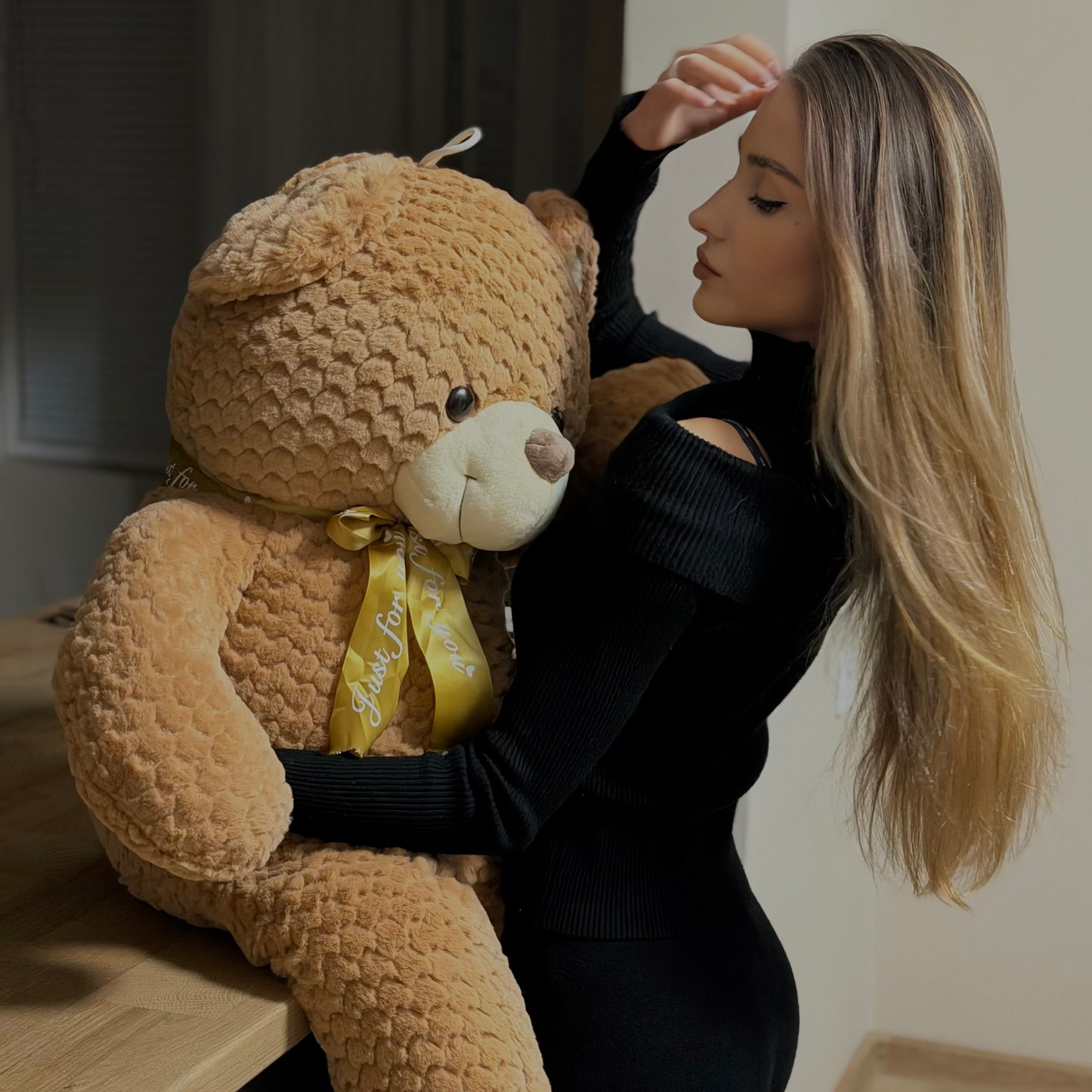 Woman holding a large teddy bear in a room with neutral colors