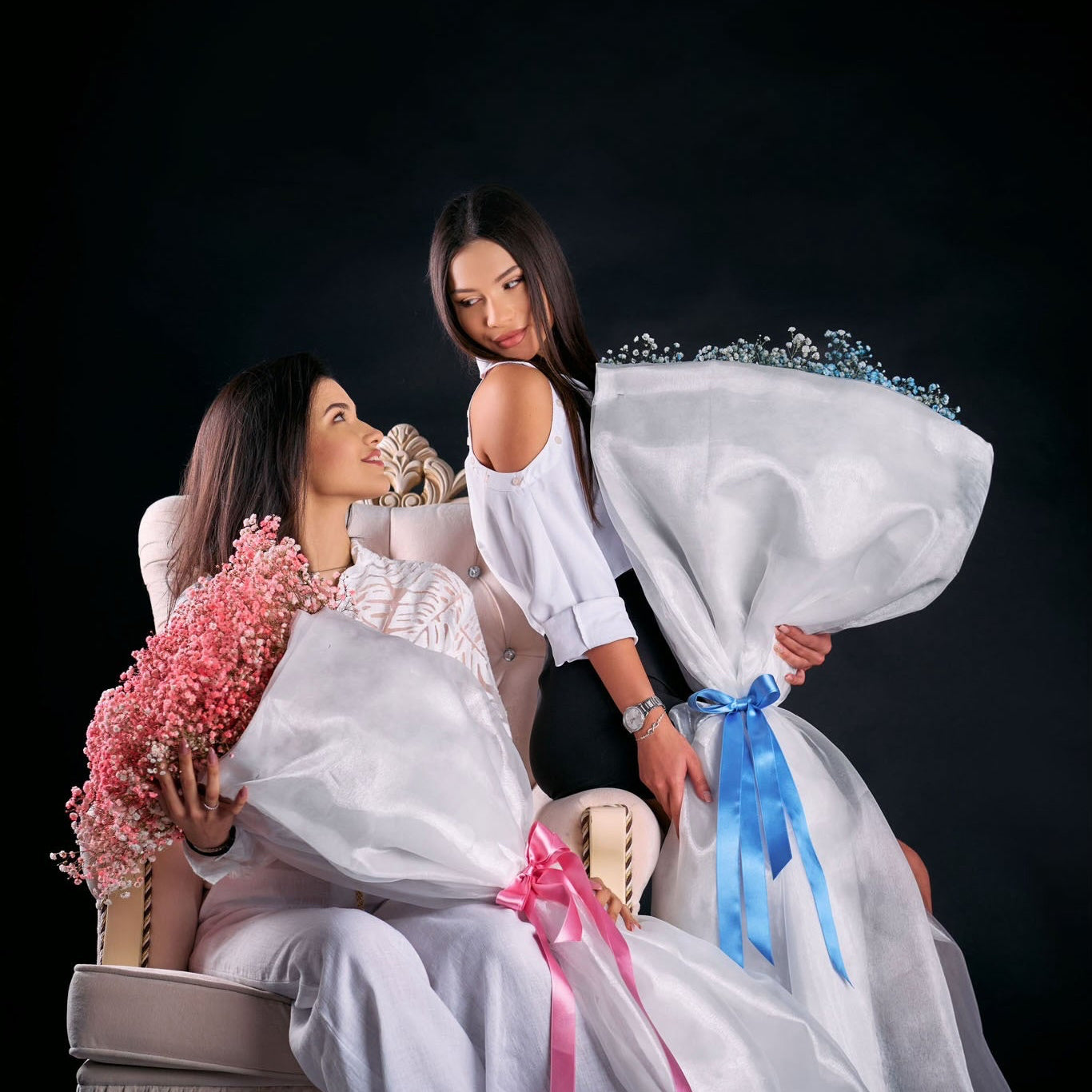 Two women with decorative pillows and flowers on a black background