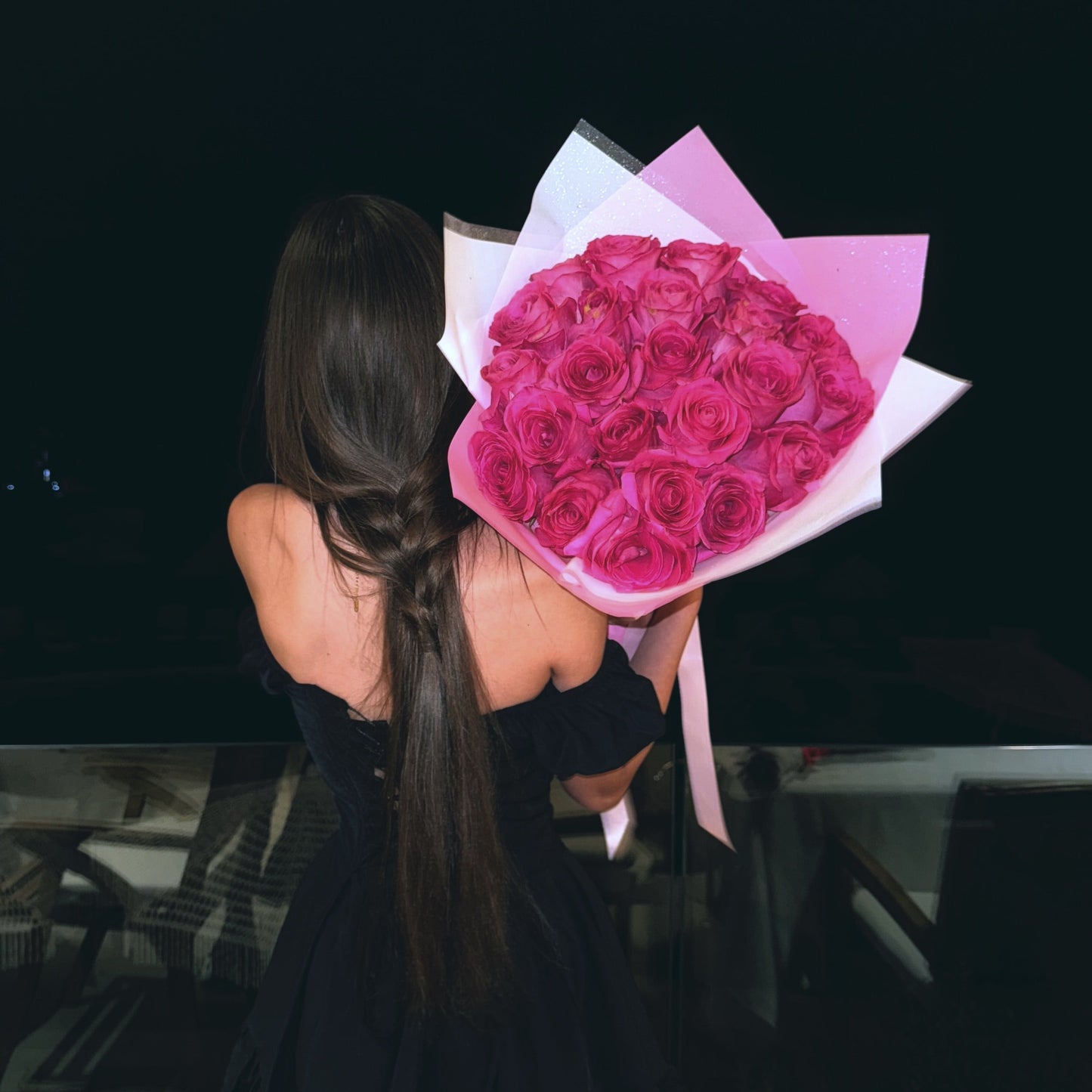Person holding a bouquet of pink roses against a dark background