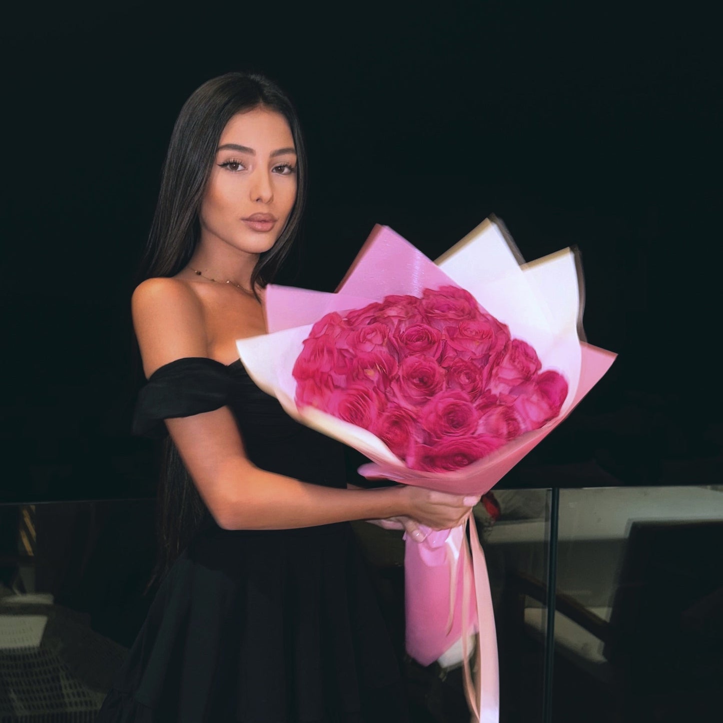 Woman holding a bouquet of pink roses against a black background