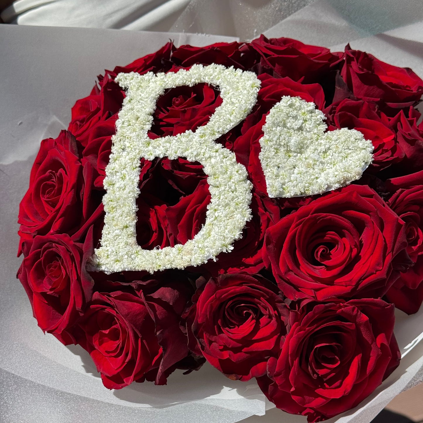 Bouquet of red roses with a white heart design on a white background