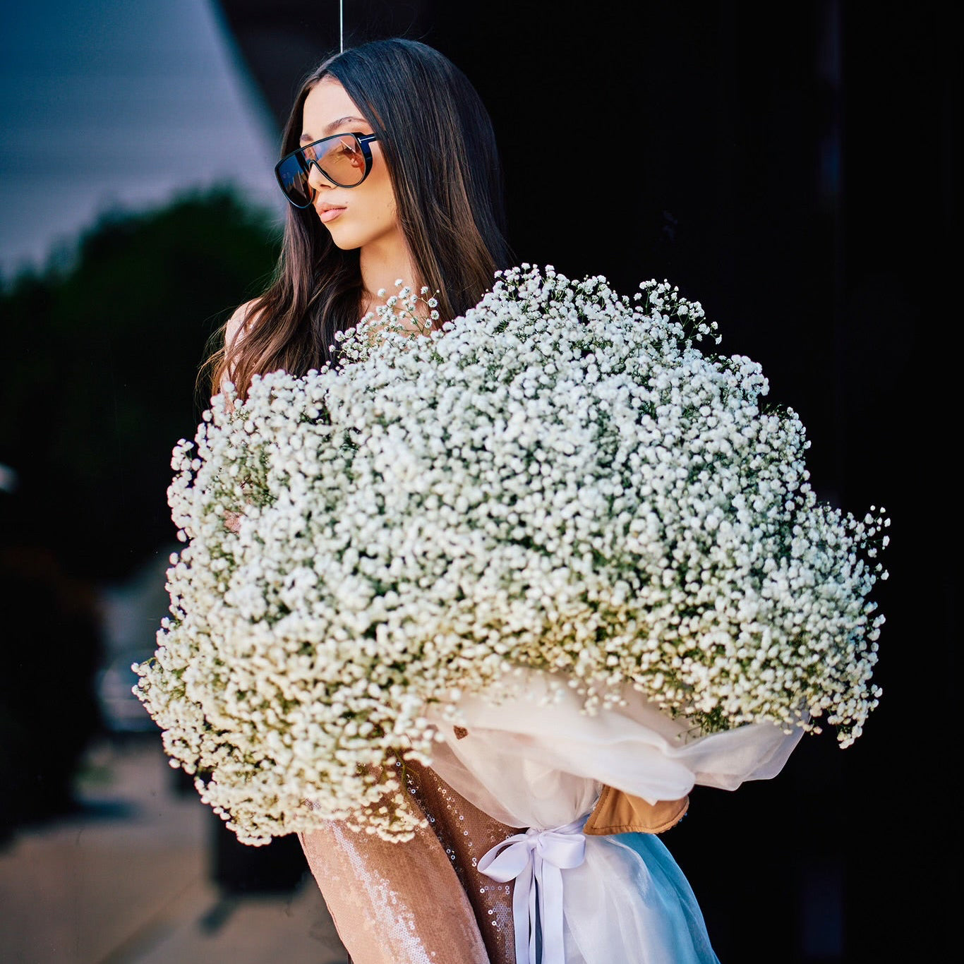Woman holding a large bouquet of white flowers against a dark background